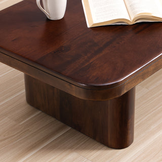Close-up of the Cinder coffee table corner, showing the thick rounded top and a slab leg