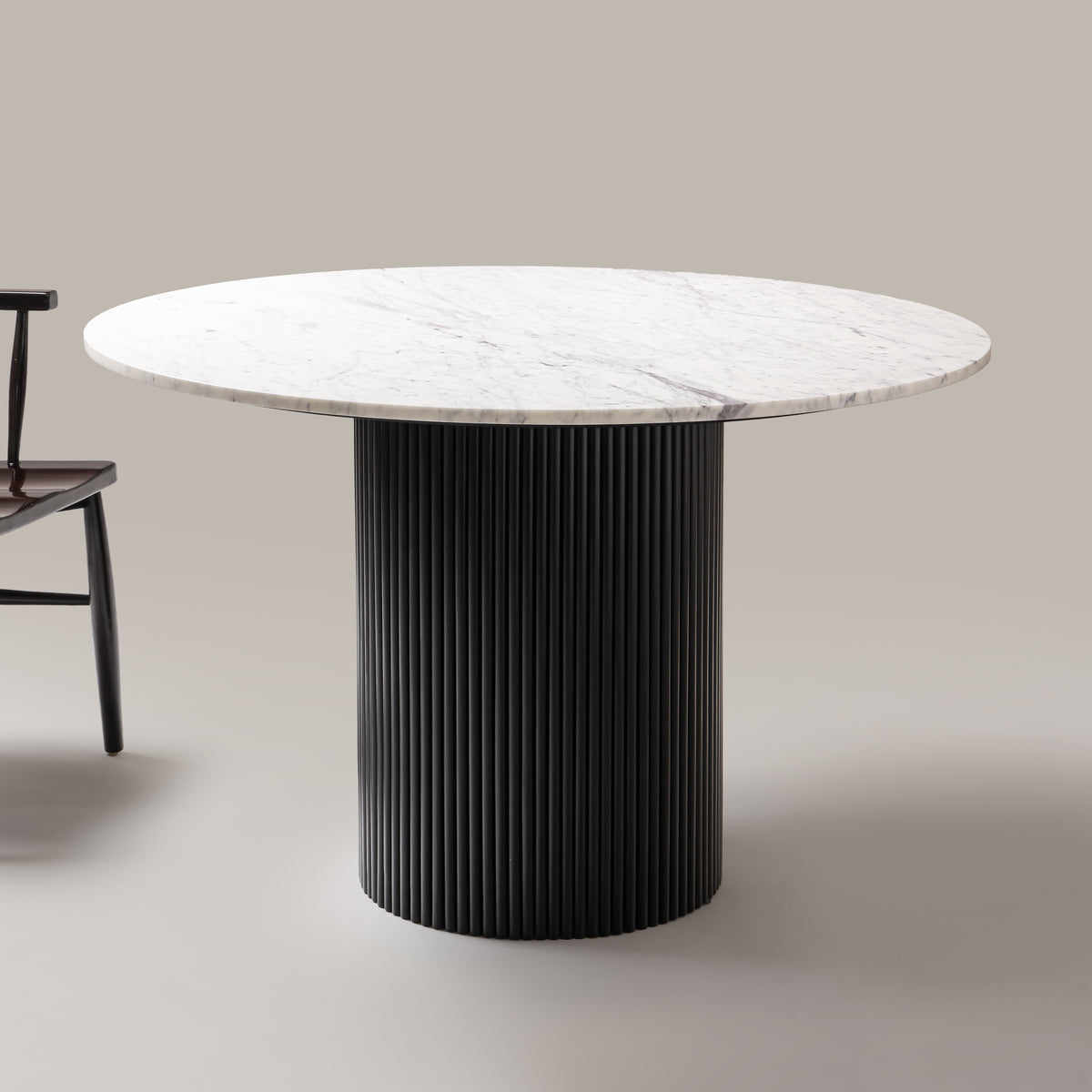 Kelby round marble dining table with black base beside a chair