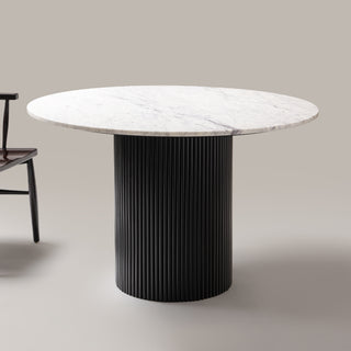 Kelby round marble dining table with black base beside a chair